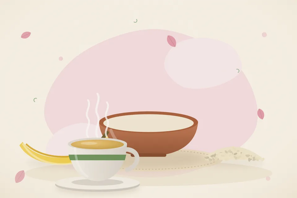 A ripe banana on a plate beside a small bowl of roasted sesame seeds and a teaspoon, set on a wooden kitchen table.