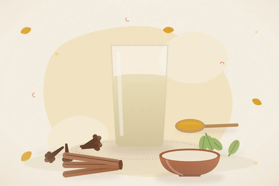 One clove, one cardamom pod and a small cinnamon piece beside a brass cup on a wooden board