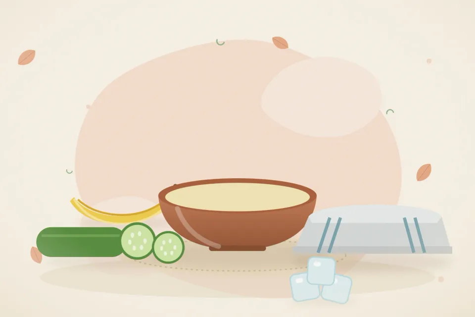 Chilled cucumber sticks, a bowl of mashed banana, a folded soft cloth and ice cubes on a peach background