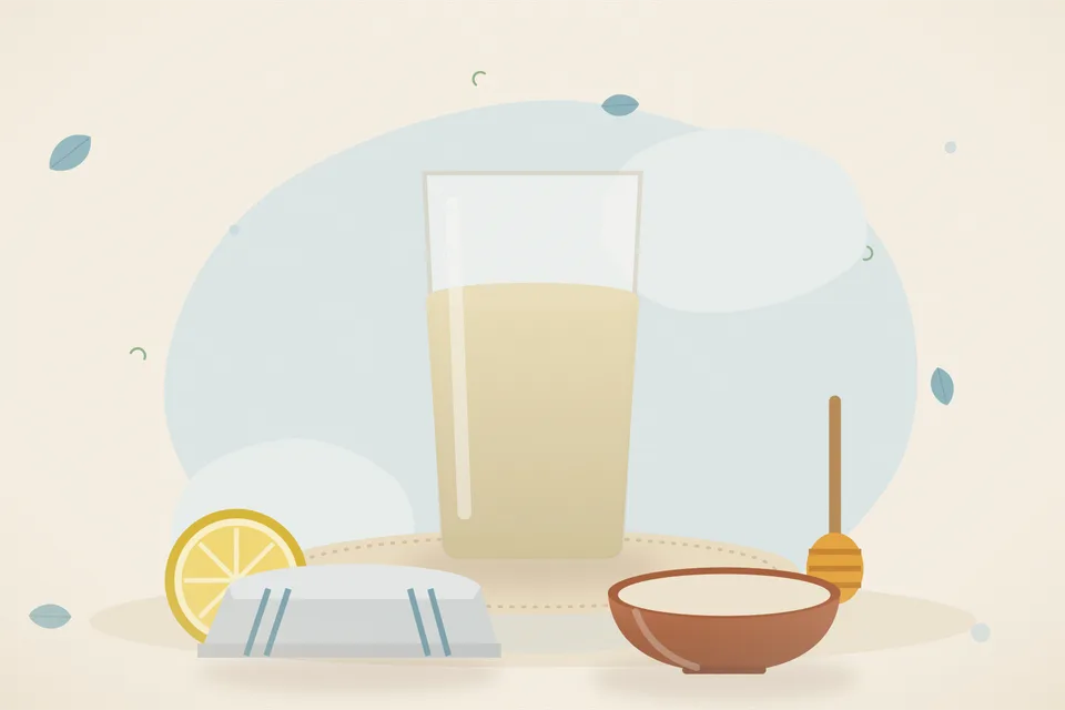 A cup of warm water, a cut lemon and a small spoon of honey on a saucer, arranged on a kitchen table.