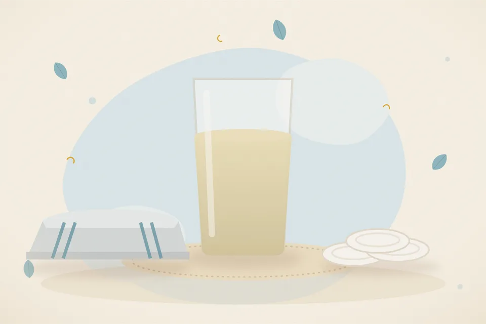 A brass cup of water on a wooden board beside a folded cotton cloth, with no writing