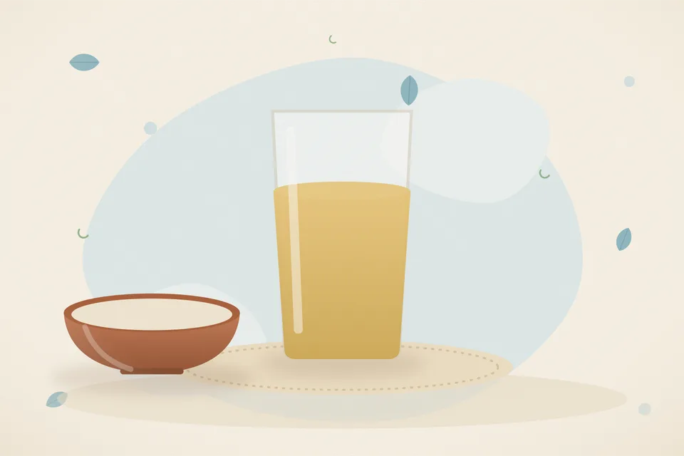 A handful of barley grains, a strainer and a glass of pale barley water on a wooden board, warm light, no people and no lettering.